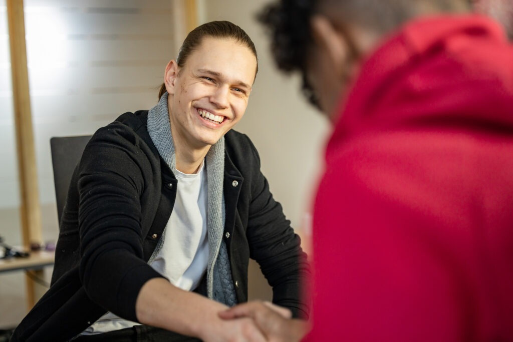 En person som smiler til en ungdom som har ryggen til.