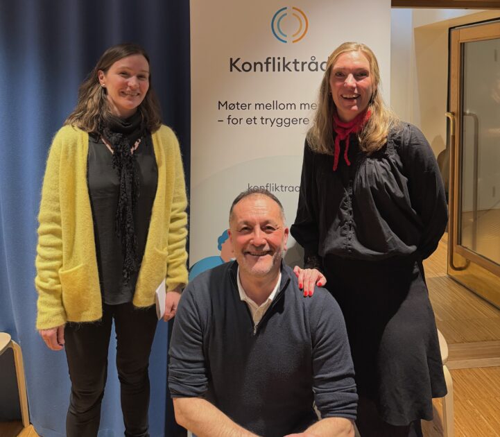 To kvinner og en mann poserer foran en roll up fra konfliktrådet.